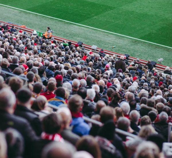 A lively crowd of soccer fans watching a game in an English stadium.